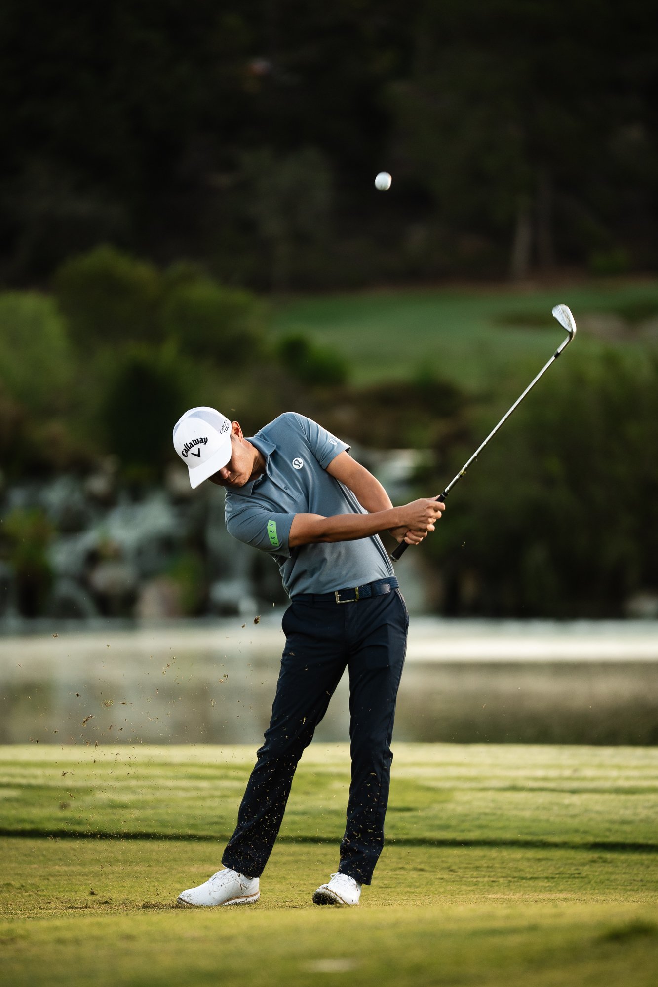 Golfer at impact on the fairway, ball in flight